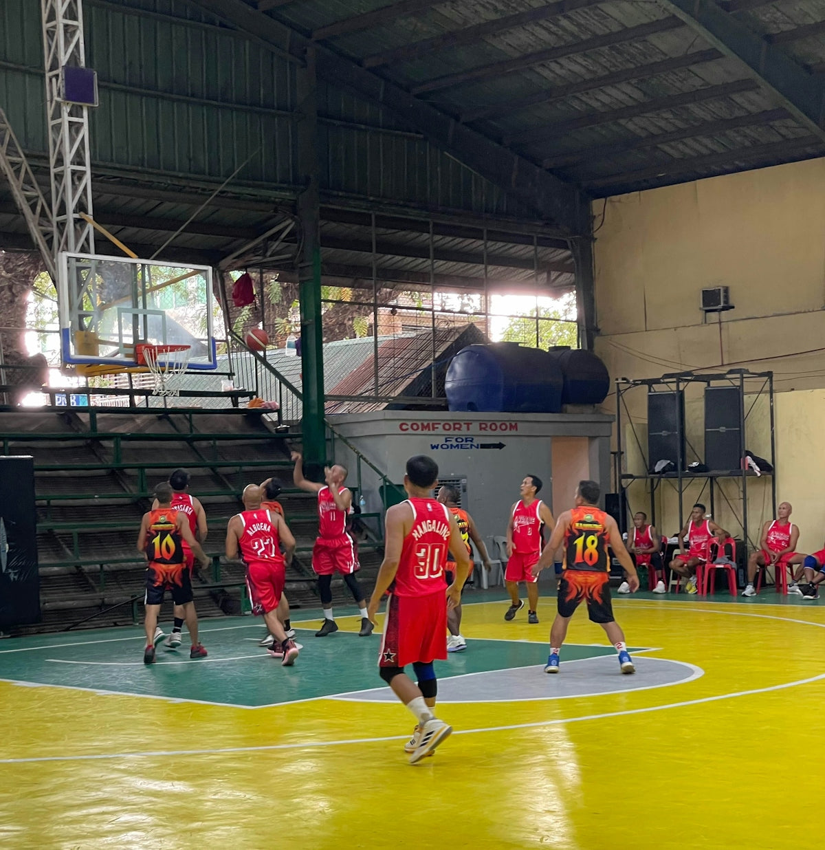 Men playing basketball in an indoor court.